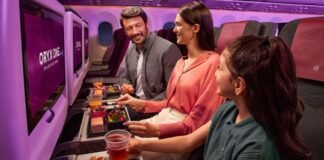 A family enjoying meals in Qatar Airways economy class with Oryx One entertainment screens