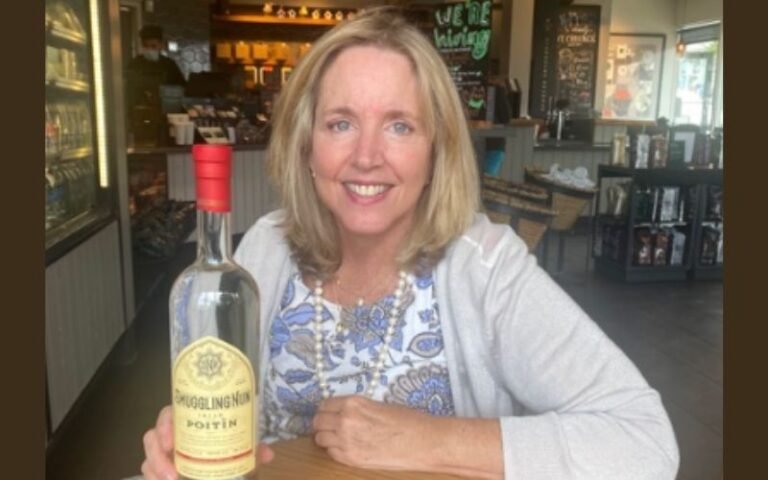 Maura Clare smiling beside a bottle of Smuggling Nun Poitín inside a cafe
